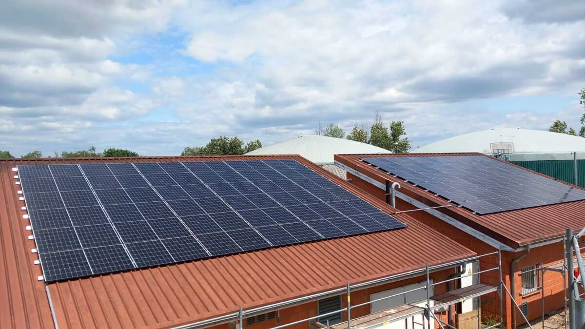 Solaranlagen auf roten Dächern eines Gebäudes unter bewölktem Himmel.