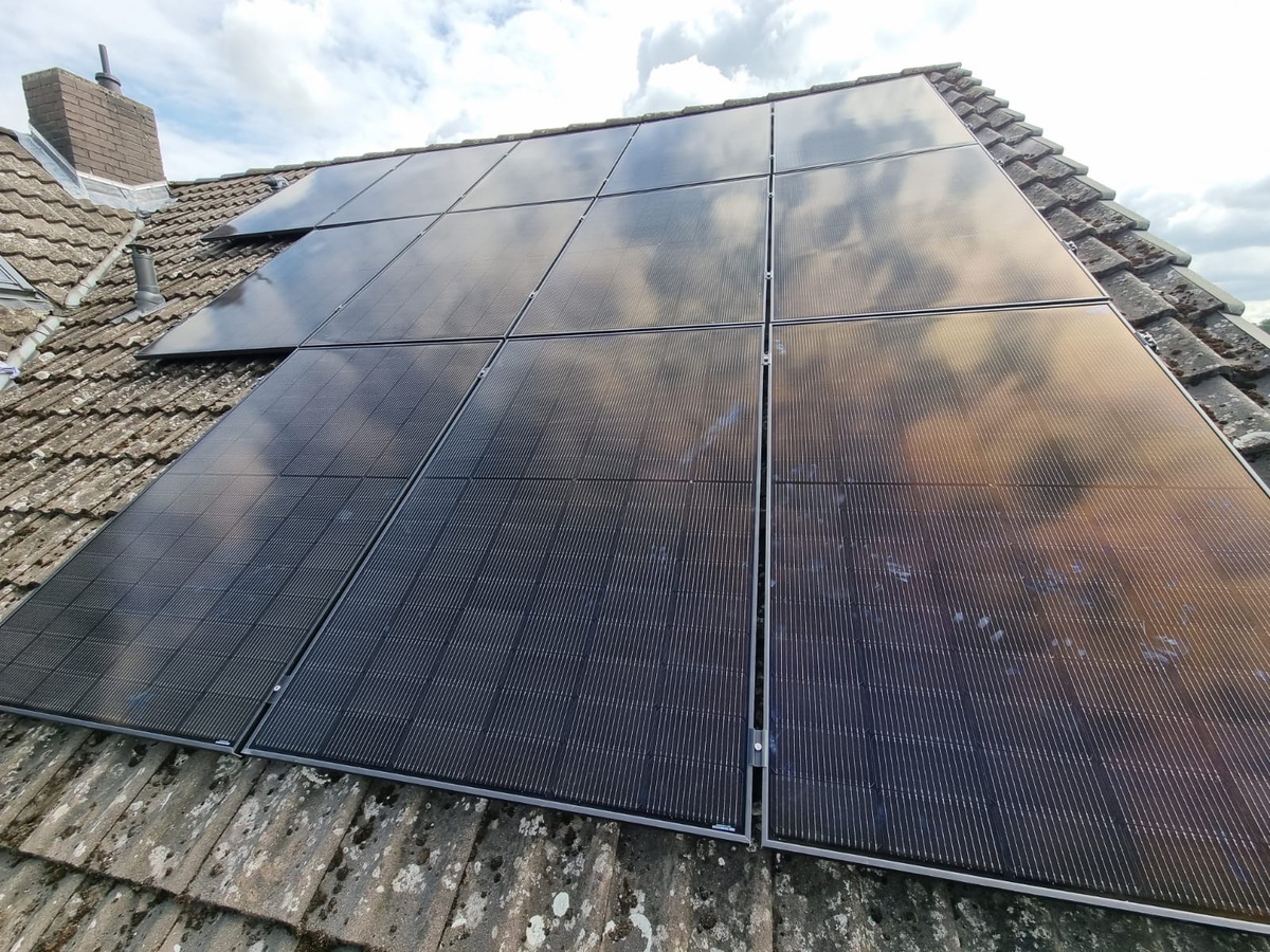 Solarmodule auf Ziegeldach, wolkiges Spiegelbild, bestehend aus mehreren Paneelen.