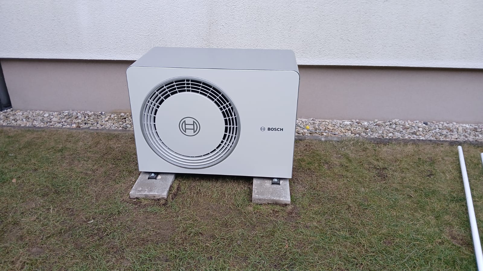 Außengerät einer Klimaanlage von Bosch, grau, auf Rasen montiert, mit Lüftergitter vorne.