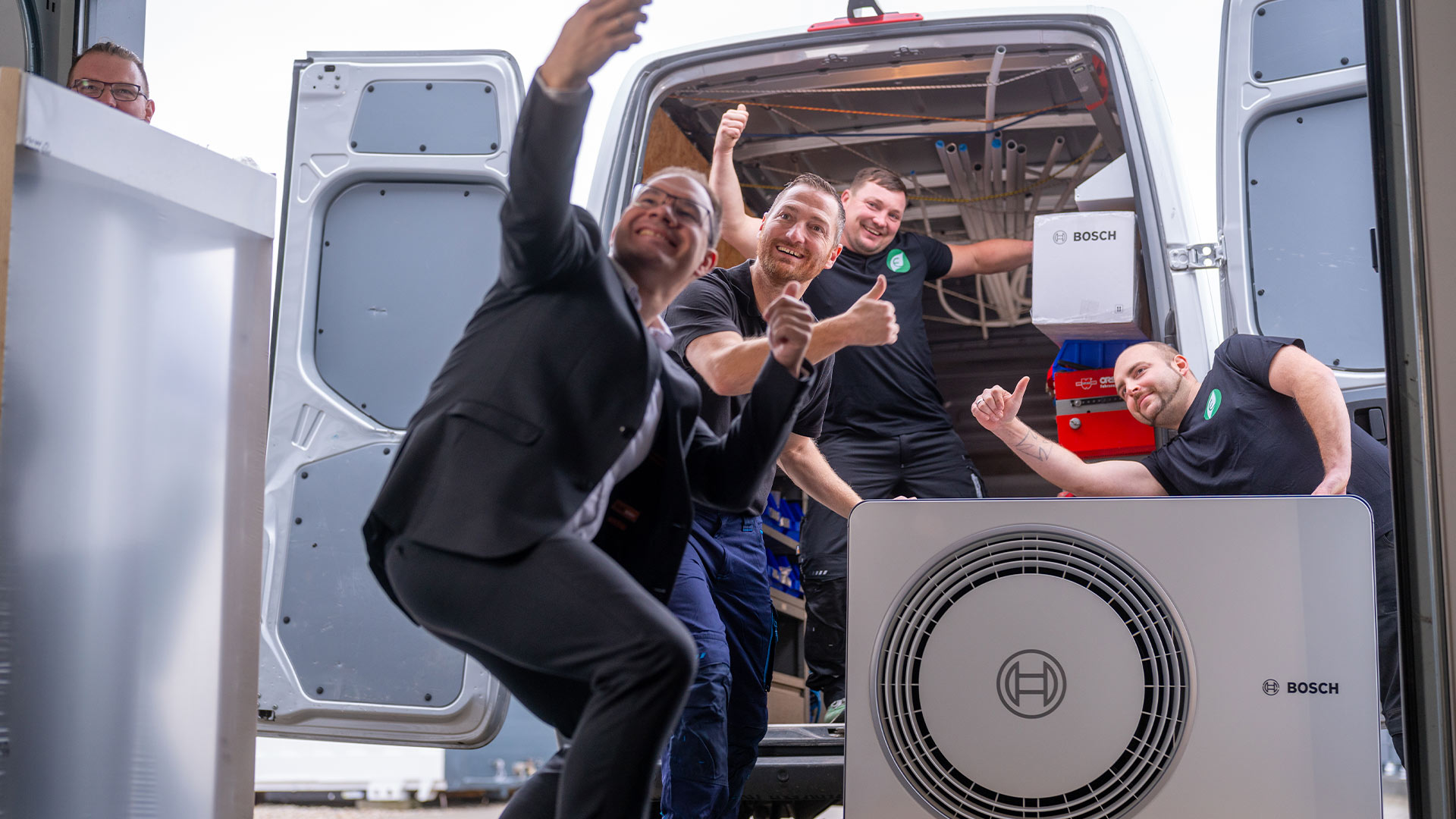 Vier lächelnde Männer machen Selfie vor Lieferwagen; im Vordergrund Bosch-Klimagerät.