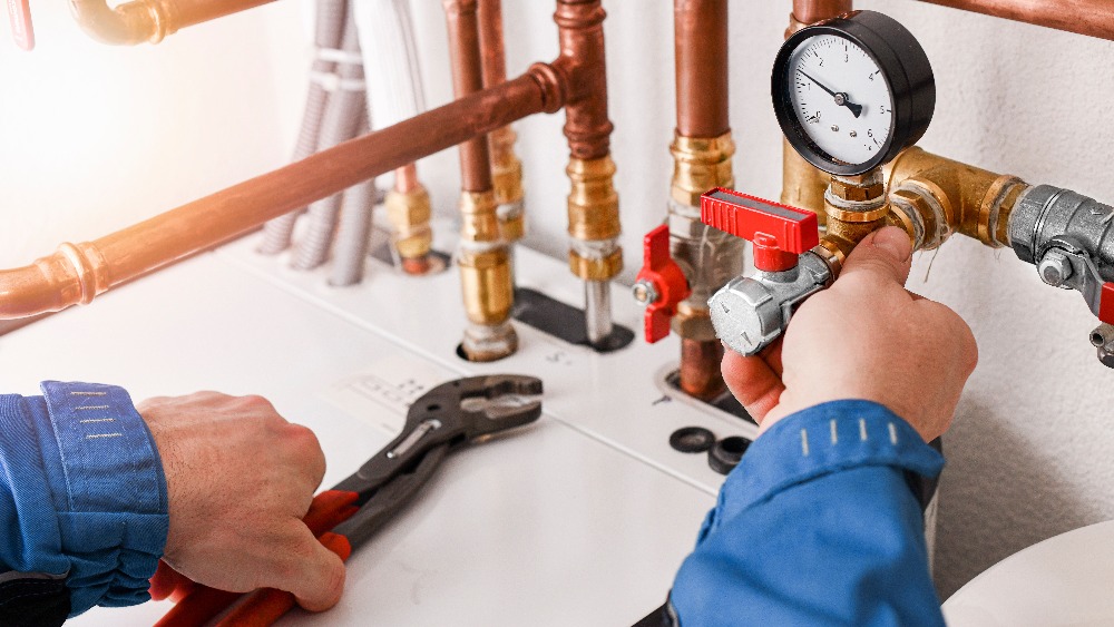 Plumbing concept or service worker. Copper pipelines close up with analog pressure gauge.