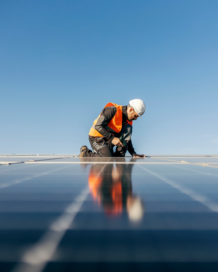 Worker kneeling and sets solar panel.