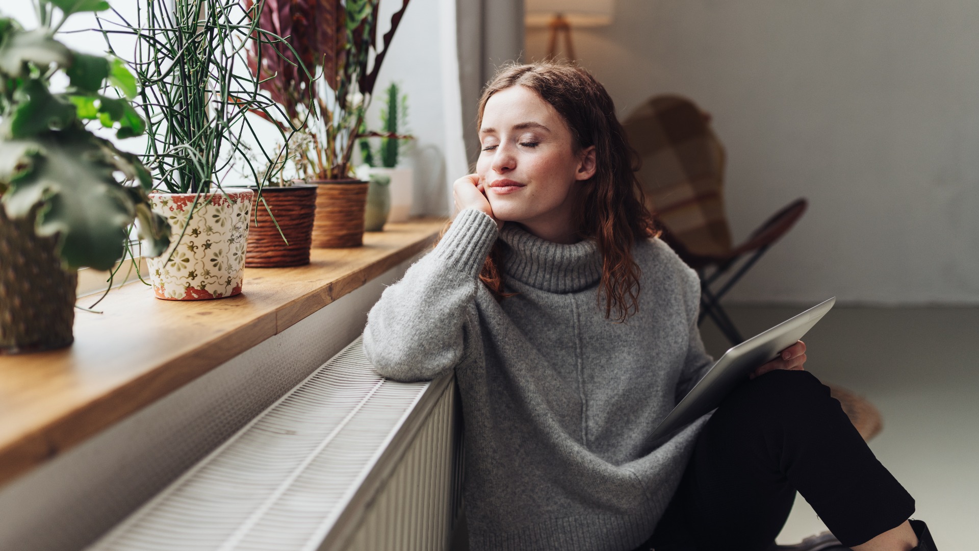 young woman relaxed at heater with tablet in hand