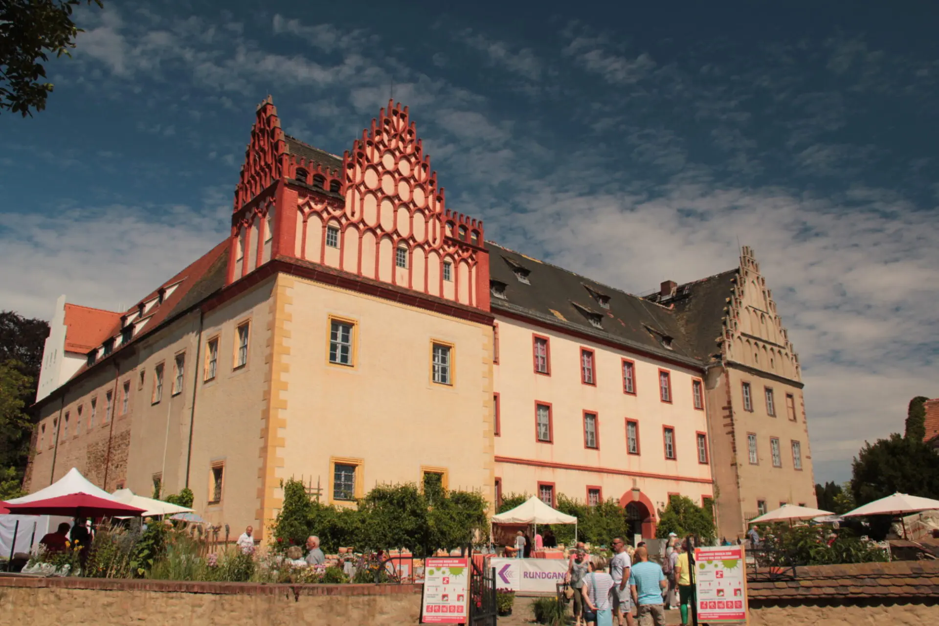 Historisches Schloss mit bemalter Fassade, Besuchermenge, blauer Himmel.